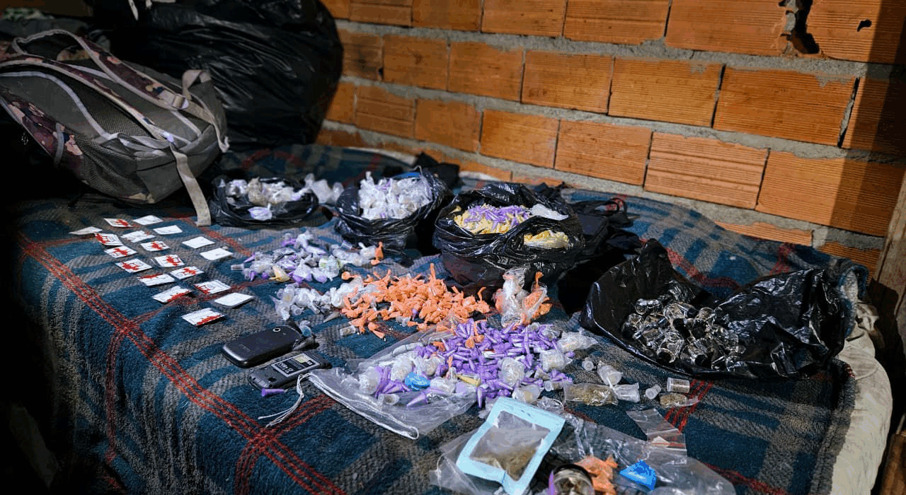 GCM Desarticula "Casa-Bomba" e Apreende Quase 1.500 Drogas em Itaquá Operação Linha Direta, realizada na madrugada, resultou na descoberta de um centro de armazenamento de entorpecentes e na prisão de um homem por receptação. A segurança pública de Itaquaquecetuba deu um passo importante no combate ao tráfico de drogas. Na madrugada desta sexta-feira (14/11), a Guarda Civil Municipal (GCM) desarticulou uma "casa-bomba"—termo usado para designar endereços de armazenamento de grandes quantidades de drogas—durante a realização da Operação Linha Direta. A ação da GCM foi desencadeada após uma denúncia anônima levar os agentes até uma residência no Jardim Miray. Ao inspecionar o local, os agentes encontraram uma quantidade expressiva de entorpecentes: um total de 1.470 porções de drogas, incluindo os perigosos "drogas k", além de crack, cocaína e lança-perfume. Para dar mais detalhes sobre o esquema criminoso, também foram apreendidas anotações que detalham a contabilidade do tráfico. Reforço na Segurança e Prisão por Receptação A Operação Linha Direta, que contou com a mobilização estratégica de 20 viaturas para coibir roubos e o tráfico, não se limitou ao Jardim Miray. Os agentes da GCM percorreram mais de 50 bairros do município, reforçando o patrulhamento. Durante estas rondas, houve outro resultado positivo: a recuperação de uma motocicleta roubada no bairro Parque Recanto Mônica. Na mesma ocorrência, um homem foi detido e será responsabilizado pelo crime de receptação. A GCM reforça o papel da denúncia anônima como ferramenta crucial para a desarticulação de crimes na cidade. Crédito da Imagem: Divulgação